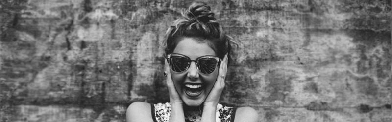 Excited girl in sunglasses holding face